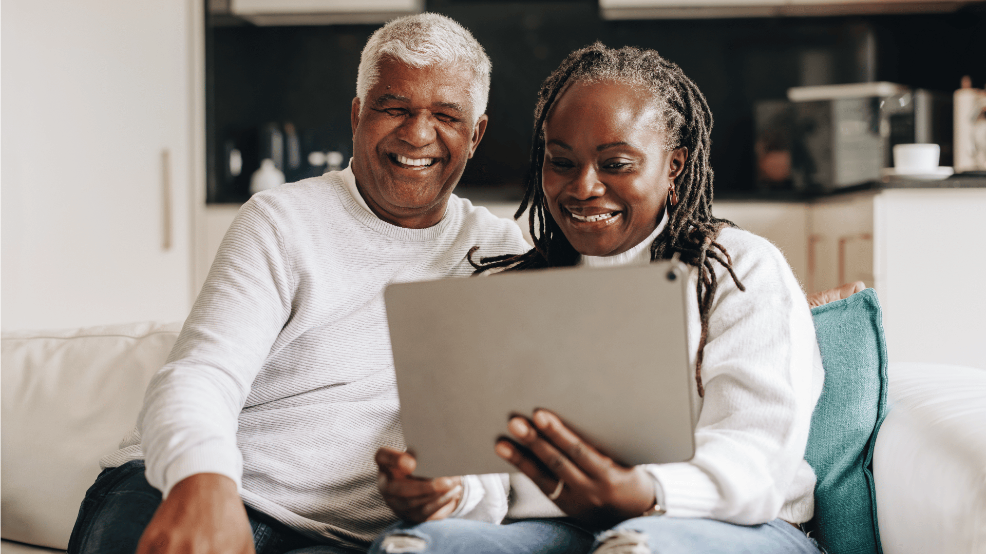 older man and woman sitting on couch using tablet to buy life insurance online