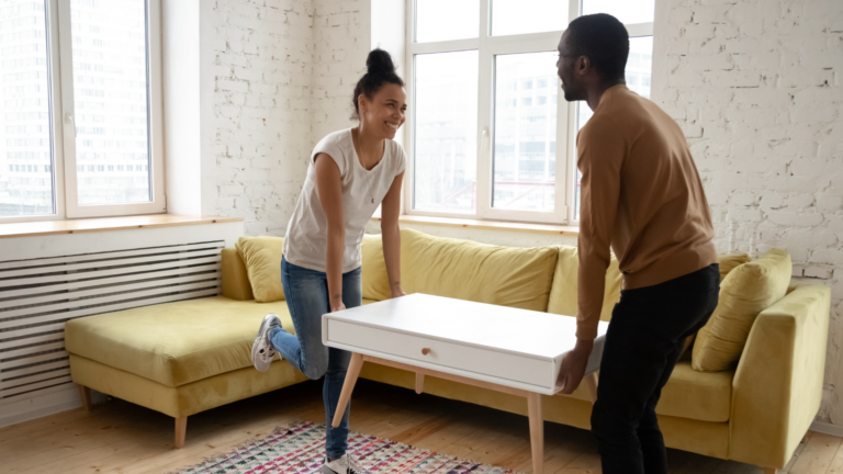 man and woman carrying a table new homeowners