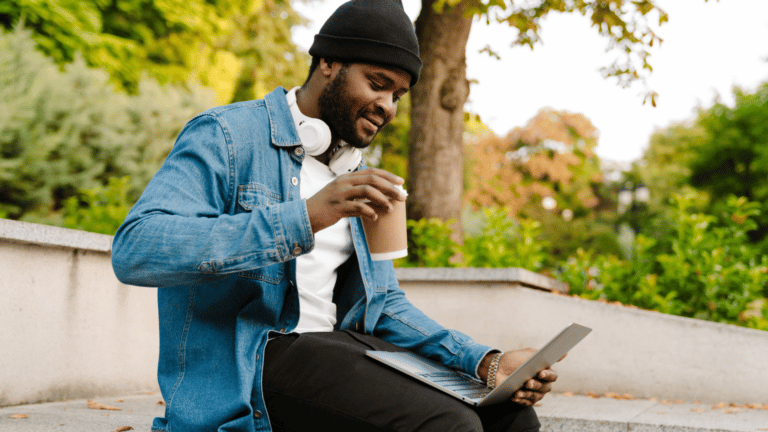 man sitting on park bench with laptop