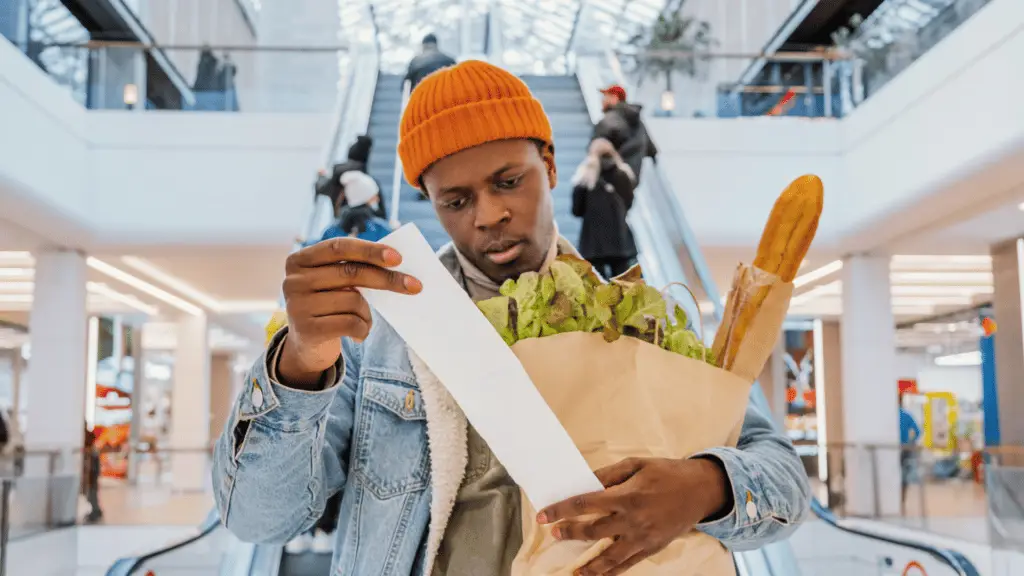 man shopping for groceries holding receipt