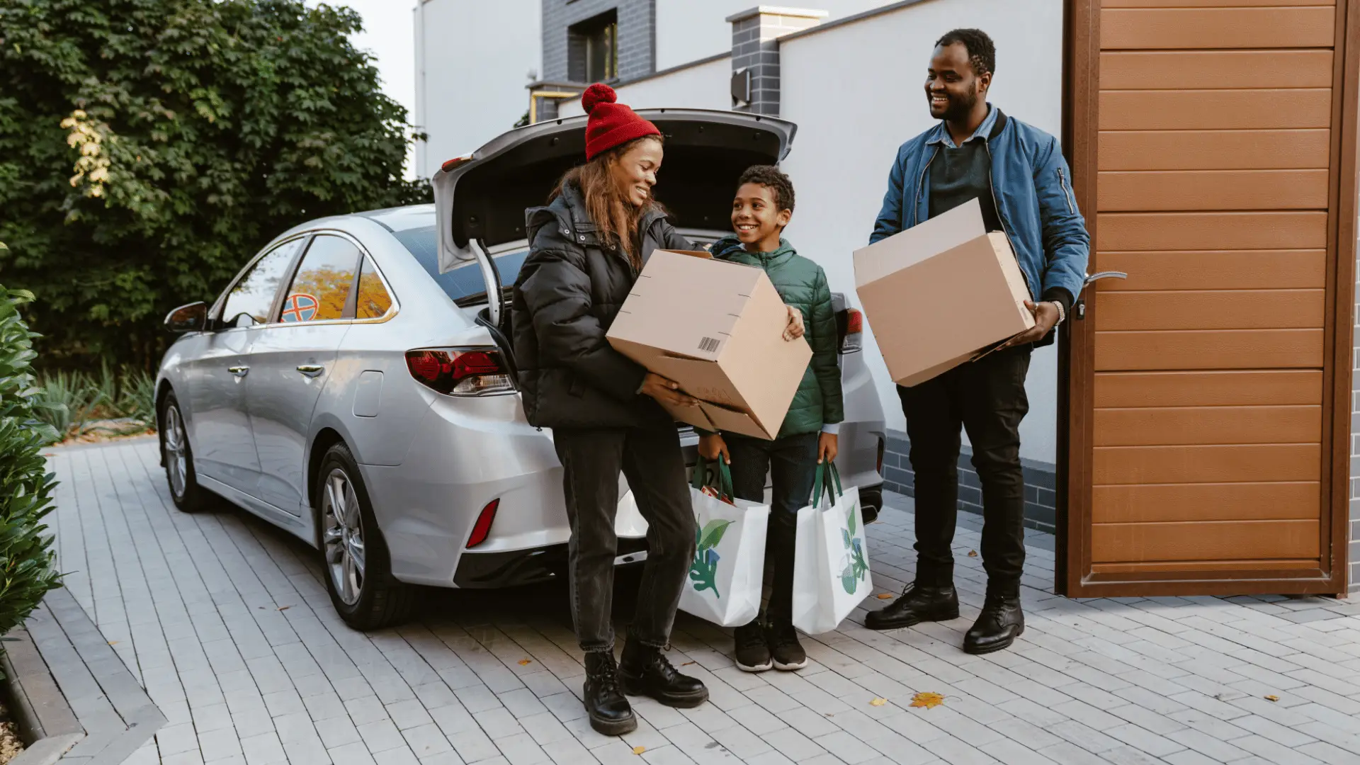 family of 3 unloading boxes from their car into new home