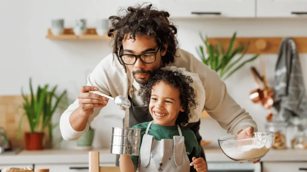 Single dad and young child cooking together in kitchen