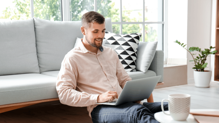 man sitting on floor looking at laptop review life insurance policy