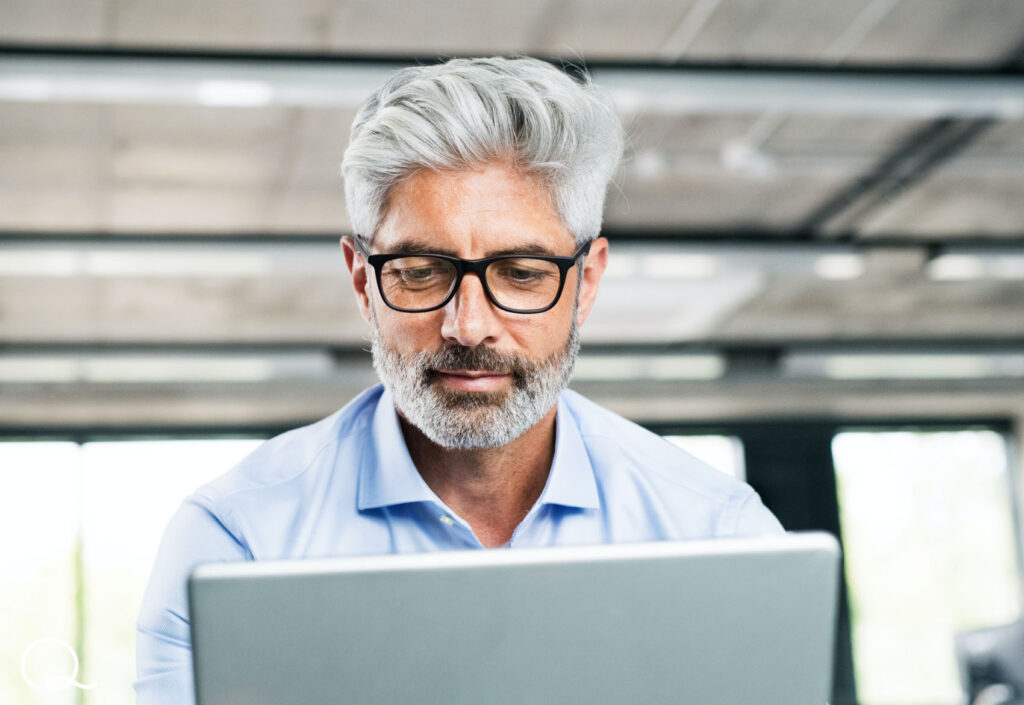 man wearing glasses looking at laptop shopping online life insurance