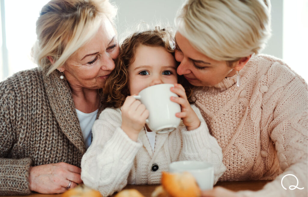 two women and young child drinking from white mug