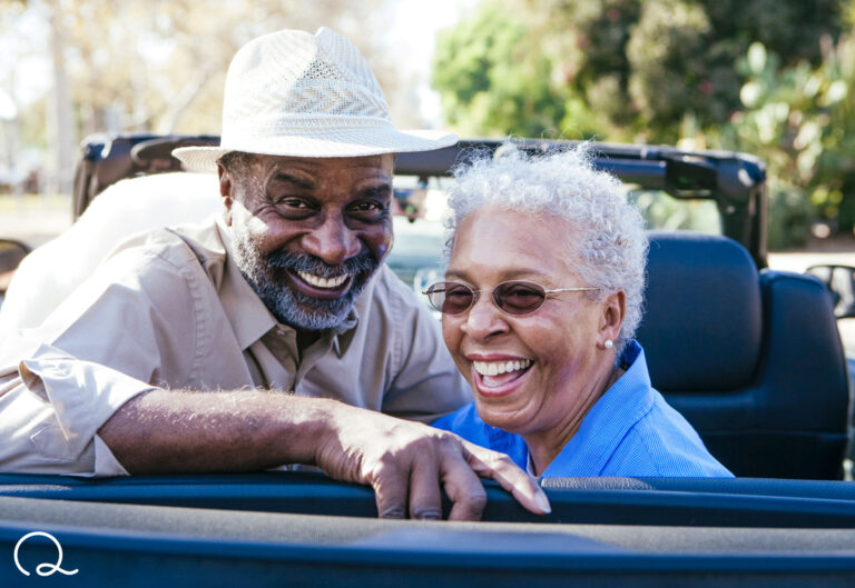 man and woman smiling riding in convertible car