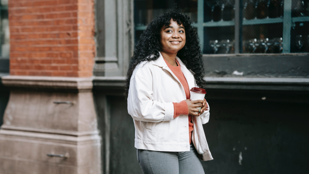 woman holding coffee standing in front of coffee shop