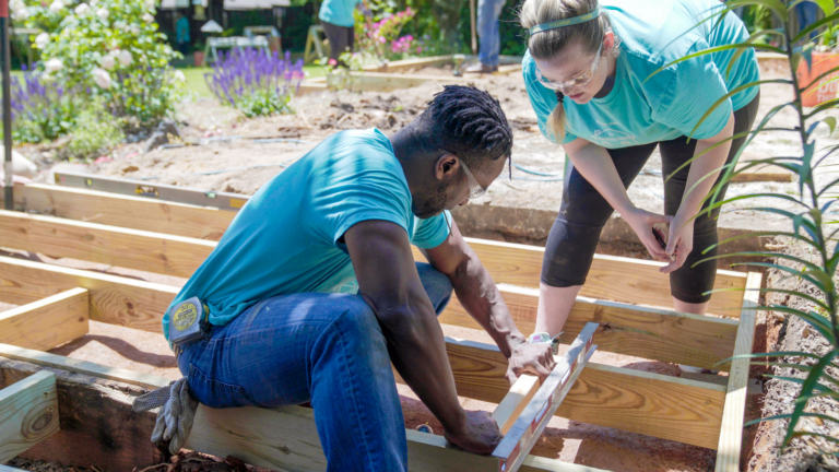 man and woman building a wood structure volunteering