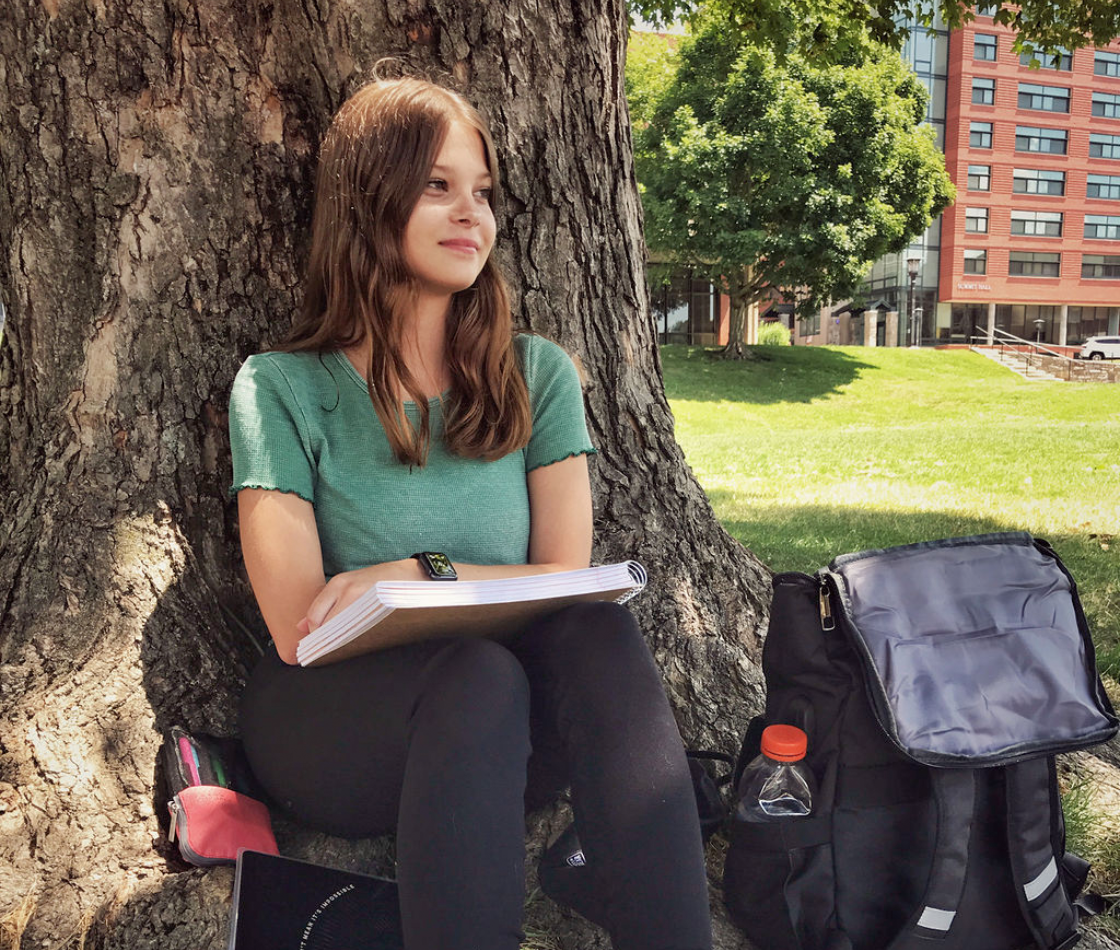 Life Lessons by Life Happens Quility scholarship recipient sitting by a tree on college campus